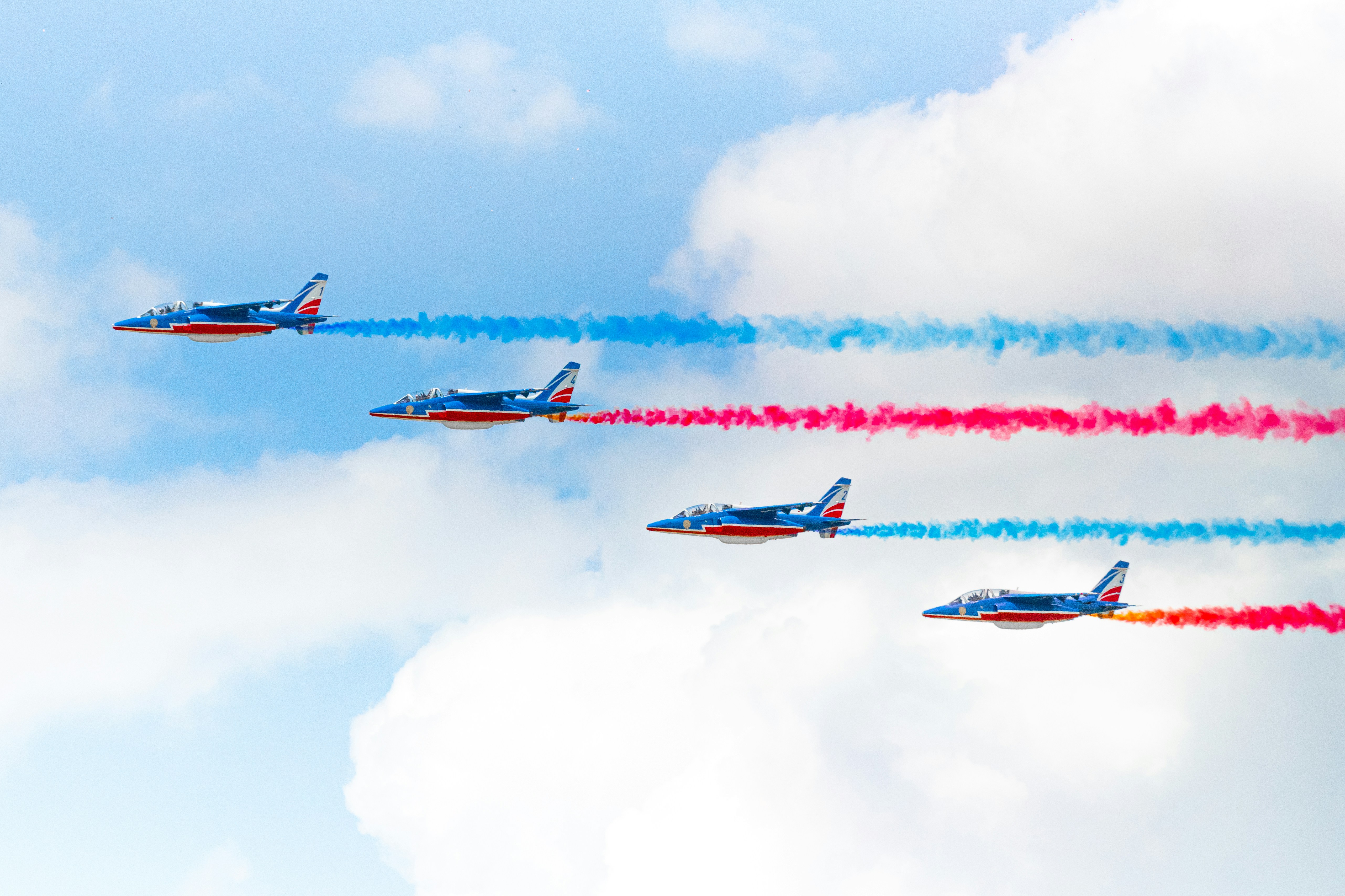 An image of some jets flying with red, white and blue smoke after them.