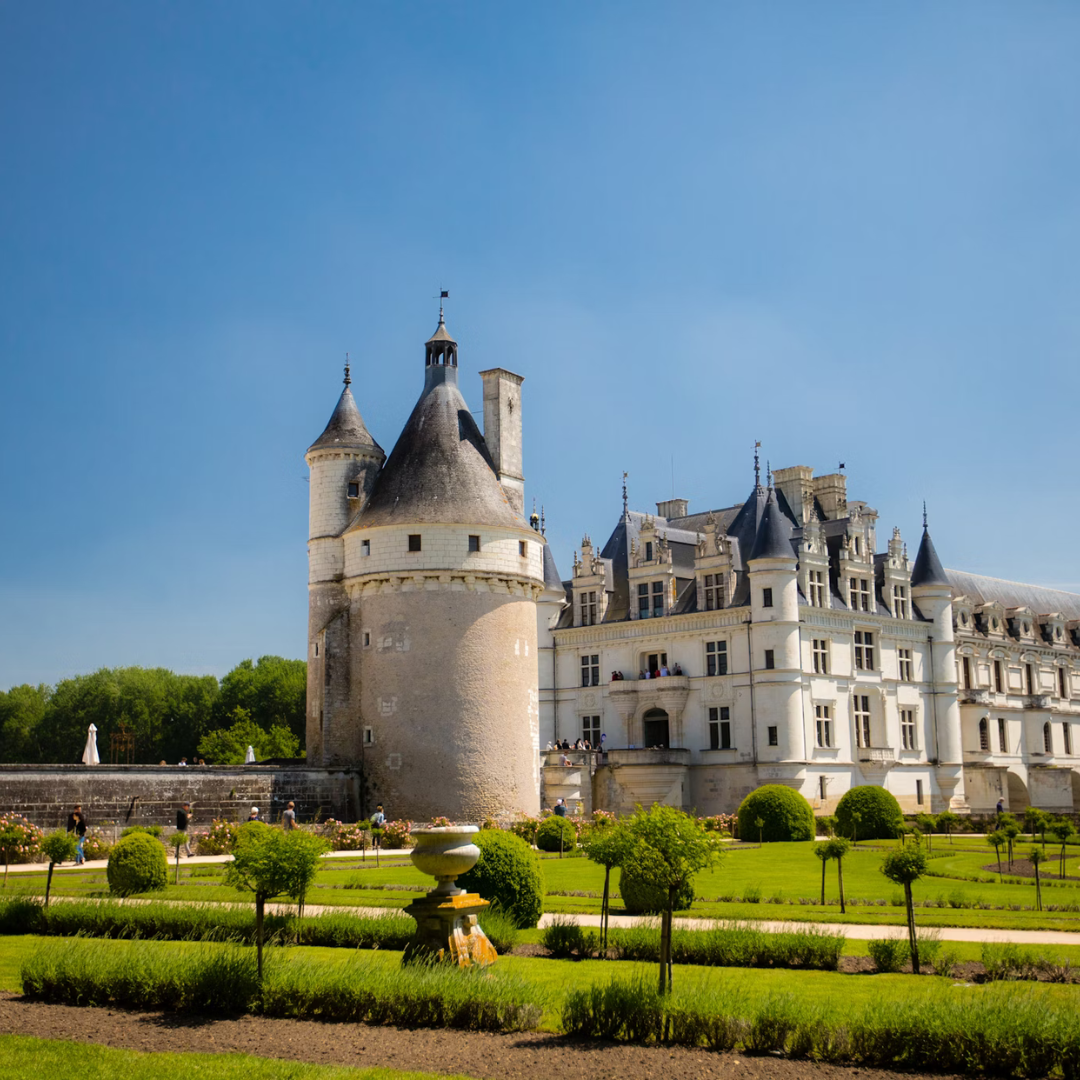 An image of the Château de Chenonceau, a castle surrounded by its green gardens.